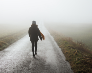 Photo d'une femme marchand dans la brume et représentant un chemin de deuil